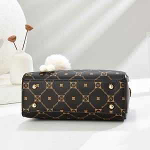 Detail view of coffee brown tote bag base with gold-tone metal feet and brand logo