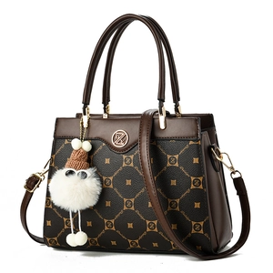 Detail of a brown leather shoulder bag with DZ logo print and cute plush charm pendant