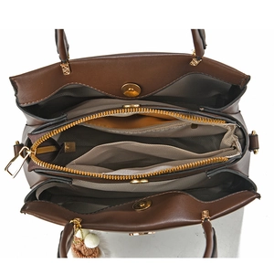 Interior view of brown handbag showing multiple compartments and smooth golden zippers