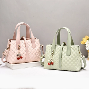 Detail of diamond-studded quilted texture with cherry charms on stylish handbags