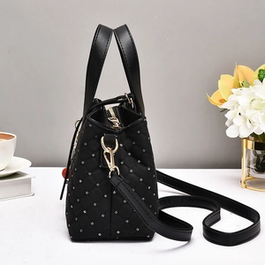 Detail of black quilted handbag with crystal studs, gold hardware, and leather strap