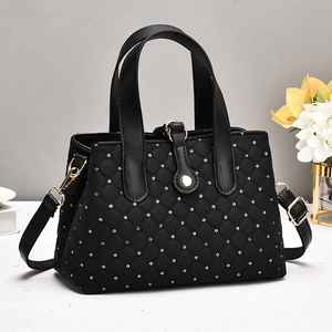 Detail of black quilted handbag with silver studs and elegant gold hardware