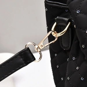 Detail of black quilted shoulder bag featuring tiny rhinestones and gold-tone hardware