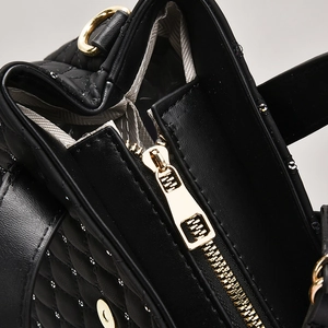 Close-up of black quilted handbag showing gold hardware and high-quality zipper detail