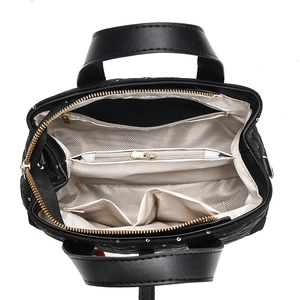 Interior layout of black quilted handbag with multiple compartments and silver rivets