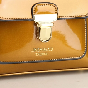 Macro shot of yellow patent leather shoulder bag with golden metallic buckle and fine stitching
