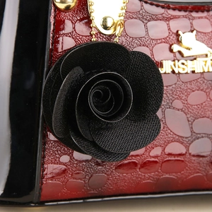 Détail macro du sac rouge texture crocodile avec rose noire et ferrures métalliques dorées