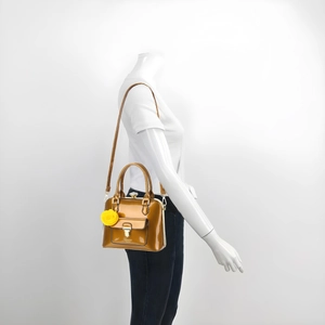 Detail of glossy amber patent leather shoulder bag with floral charm and shoulder strap