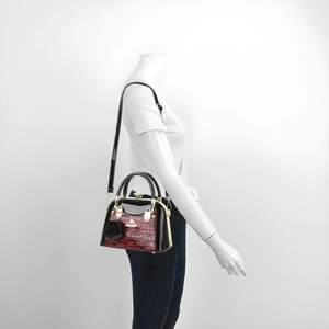 Détail du sac bandoulière en similicuir croco rouge et verni noir avec dorures