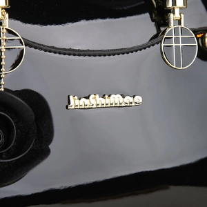 Detail of black patent leather handbag with gold JinShimao logo and floral charm
