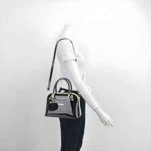 Close-up of black patent leather bag with gold hardware and black rose charm detail