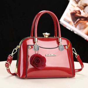 Elegant red patent leather handbag with rose charm and crystal lock on white surface