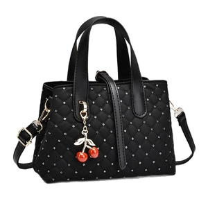 Black quilted handbag for women with silver dots and a red cherry charm accessory