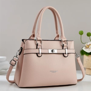 Pink lychee grain leather tote bag with silver buckle in a home setting close-up