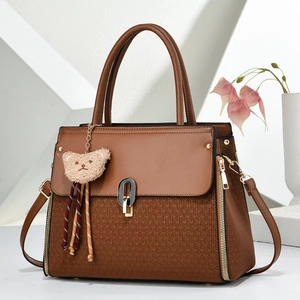 Detail of warm brown leather tote featuring V-shaped woven texture and bear pendant