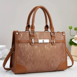 Detailed side view of the brown handbag featuring vertical texture and silver metal lock
