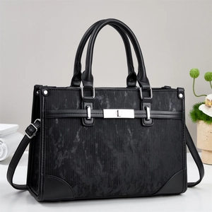 Detail of black structured tote bag with brushed texture and silver hardware accents