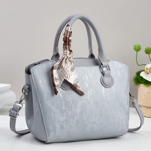 Detail of light blue textured leather handbag with elegant decorative pattern silk scarf