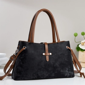 Detail of classic black and brown handbag featuring silver rivets and leather texture