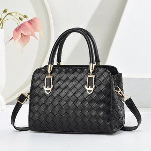 Sac cabas chic en cuir tressé noir avec détails dorés et bandoulière sur socle blanc