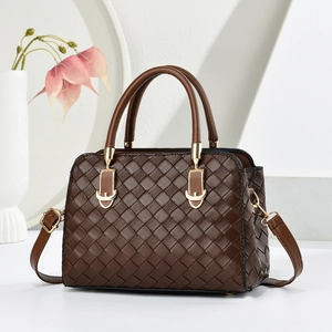 Vue détaillée de la texture tressée marron foncé et des garnitures dorées du sac à main