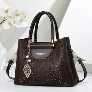 Sac à main marron foncé à motif serpent avec pendentif feuille sur support en marbre