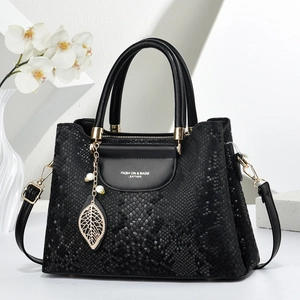 Détail du sac à main noir motif serpent avec pendentif feuille dorée et perles