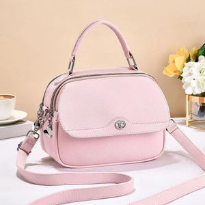 Detail of light pink lychee pattern leather handbag with metal buckle and shoulder strap