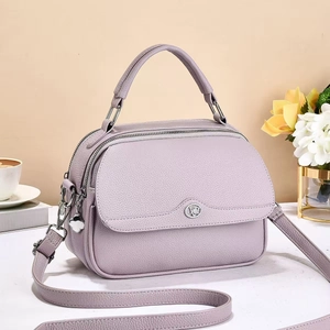 Detail of light purple lychee leather handbag with silver clover pendant and strap