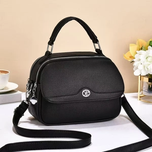 Detail of black pebbled leather handbag with double zippers and lucky clover charm