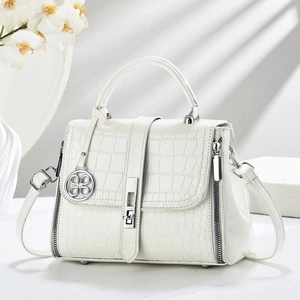 White faux crocodile leather handbag with silver lock and clover charm in soft sunlight