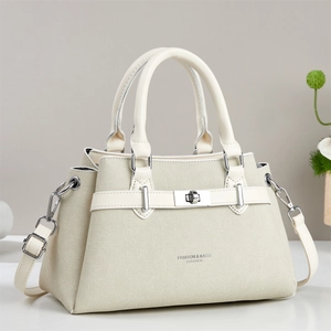 Detail of beige textured fabric handbag with metal turn-lock and leather handles