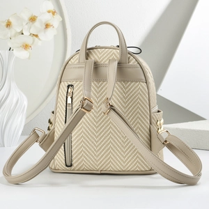 Close-up of beige woven backpack with gold rivets and hidden anti-theft zipper detail
