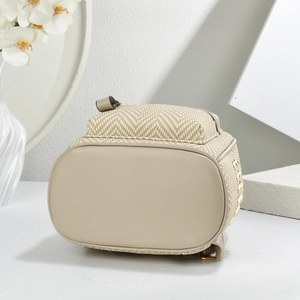 Detail of herringbone straw backpack with matte leather base and gold studded side accents