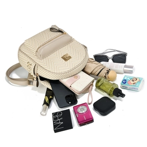 Flat lay of a beige woven backpack showing its large capacity with various daily essentials