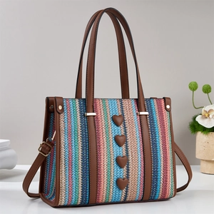 Dettaglio della borsa tote intrecciata colorata con finiture in pelle e decori a cuore