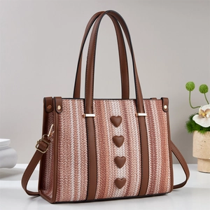 Dettaglio borsa tote intrecciata con borchie a cuore e manici in pelle in stile minimalista