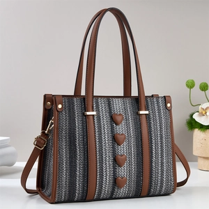 Dettaglio della borsa tote tessuta con finiture in pelle marrone e quattro cuori