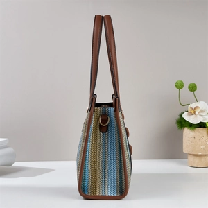 Dettaglio della borsa tote tessuta a righe con motivi multicolore e manici in pelle