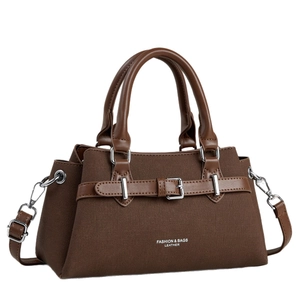 Modern dark brown canvas and leather handbag with adjustable strap on white background