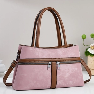 Pink two-tone satchel bag with brown handles and dual silver zippers on gray background