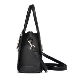 Detail view of black faux leather handbag with pearl flower charm and gold hardware