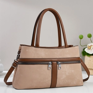 Detail of khaki suede handbag with double zippers, round handles and adjustable strap
