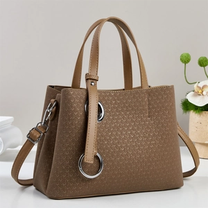 Close-up of woven texture and metallic ring detail on dark brown tote bag