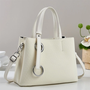 Detail showing creamy white leather tote bag with subtle V-shaped woven texture and silver ring