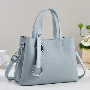 Detail of light blue tote bag with textured leather, silver ring buckle and shoulder strap
