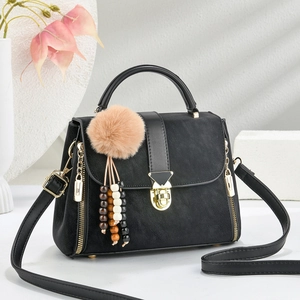 Elegant black minimalist tote bag with gold hardware and plush pompom charm detail