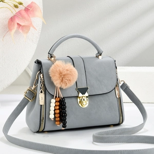 Light grey shoulder bag with gold hardware and plush charm on a clean background