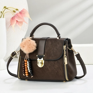 Close-up of a vintage brown matte crossbody bag with a gold lock and plush charm
