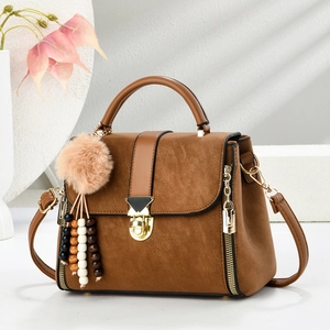 Elegant caramel brown leather handbag with gold twist lock and colorful tassel charm
